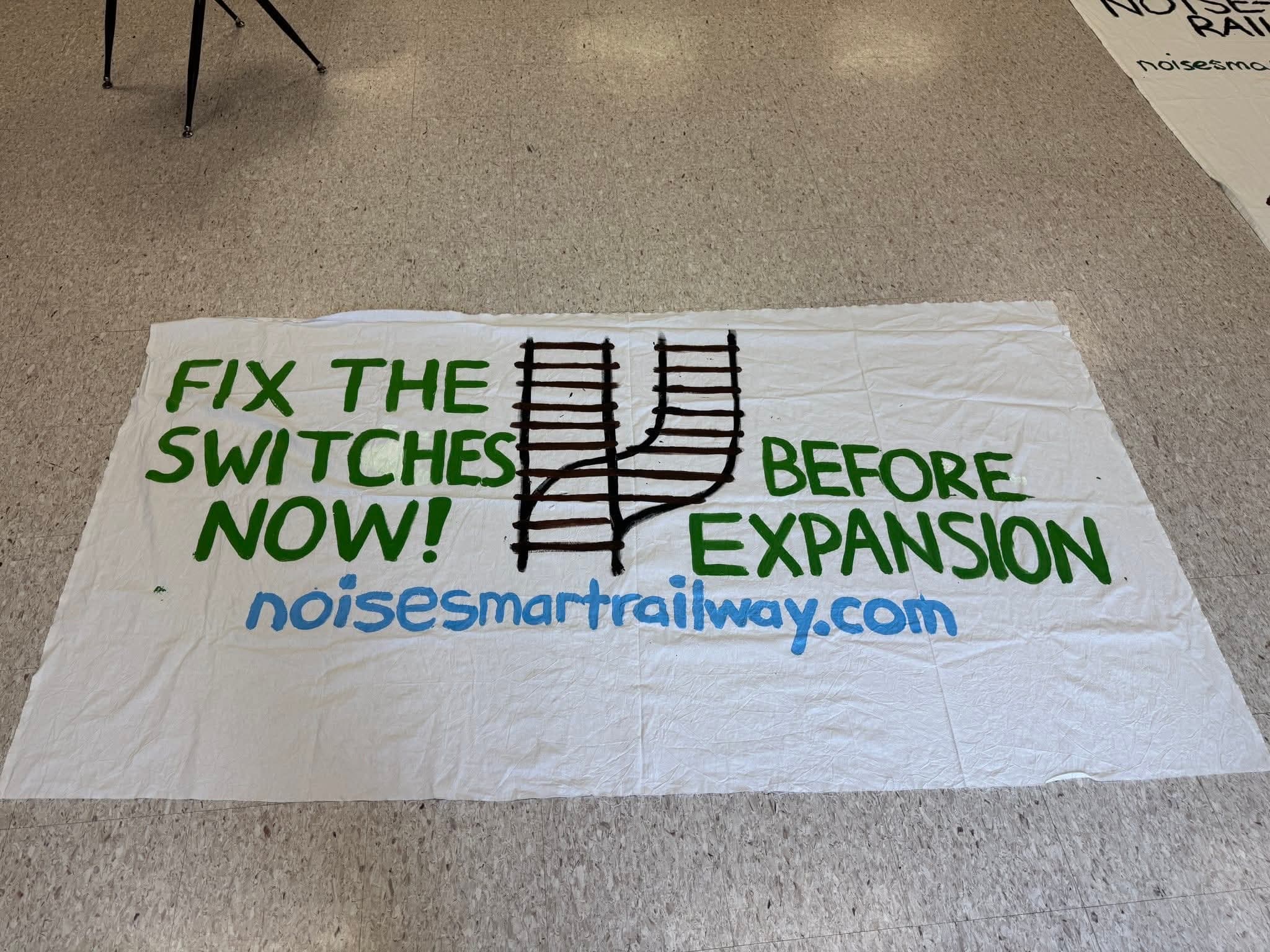 Hand-painted banner reading Fix the Switches Now! Before Expansion — noisesmartrailway.com