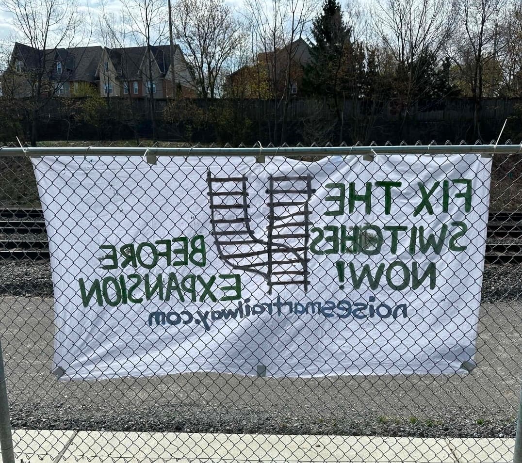 Community banner displayed on fence facing the railway tracks